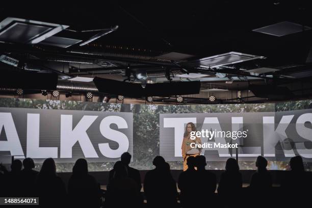 female pubic speaker giving speech to audience at convention center - conference center stockfoto's en -beelden