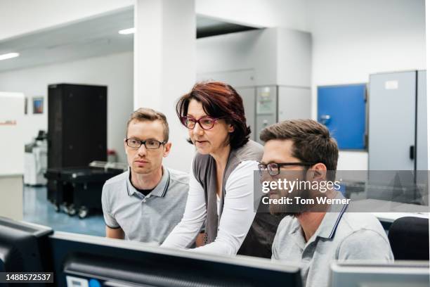 mature female programmer guiding two engineers - old servers stock pictures, royalty-free photos & images