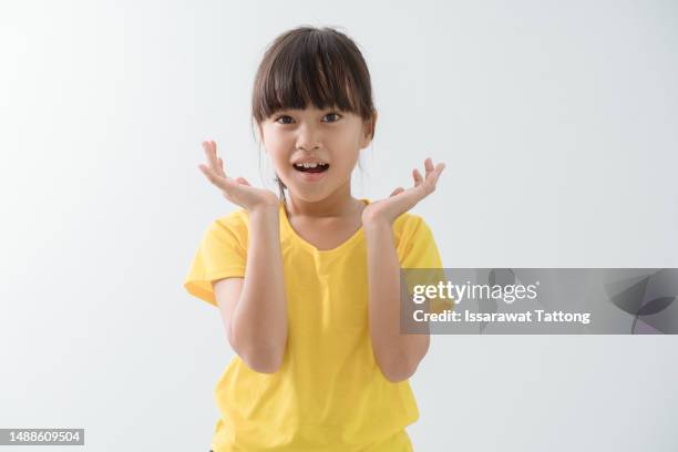 portrait of a shocked little girl holding hands at her face and looking at camera isolated over white background - young girl white background stock pictures, royalty-free photos & images