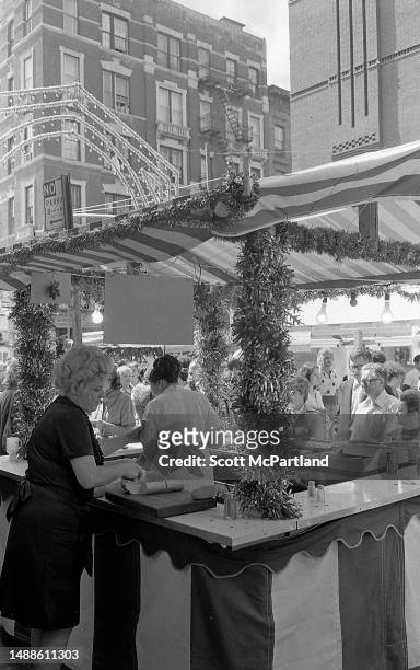 Vendor slices Italian bread on a cutting board at a booth on Mulberry Street during the Feast Of San Gennaro Festival, in the Little Italy...