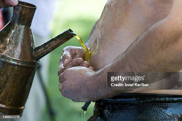 wrestler pouring olive oil on himself at edirne 2008 kirkpinar oil wrestling tournament. - middle east oil stock pictures, royalty-free photos & images