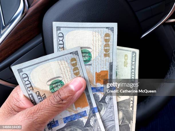 black woman sitting in driver’s seat in vehicle holding $220 in paper bills - american twenty dollar bill stock pictures, royalty-free photos & images