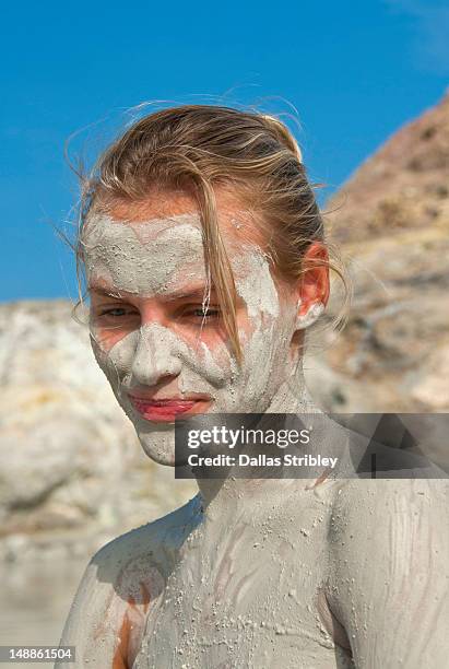 mud-covered young woman bathing at the therapeutic volcanic thermal mud pool, levante beach. - schlammbad stock-fotos und bilder