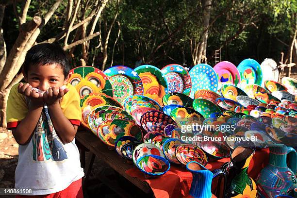 young boy at a stall selling colourful ceramic plates. - artesanias mexicanas fotografías e imágenes de stock