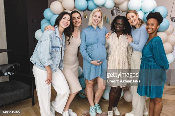 a happy group of friends hugging and posing for a photo at baby shower party - babyshower stockfoto's en -beelden
