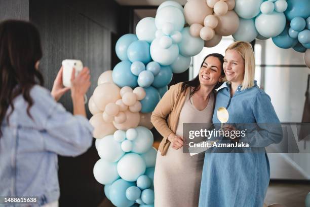 taking polaroid photos at a baby shower celebration - babyshower stockfoto's en -beelden