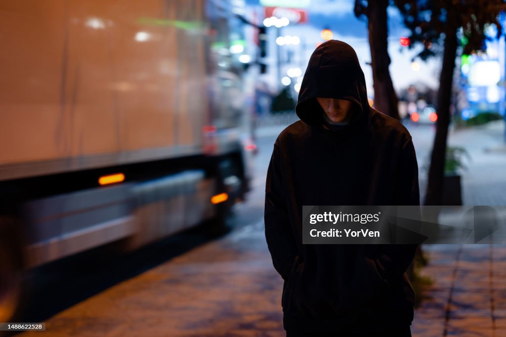 Faceless man with a black hoodie in the night city