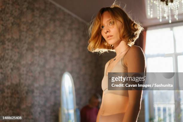 attentive woman in short top at home - slank stockfoto's en -beelden