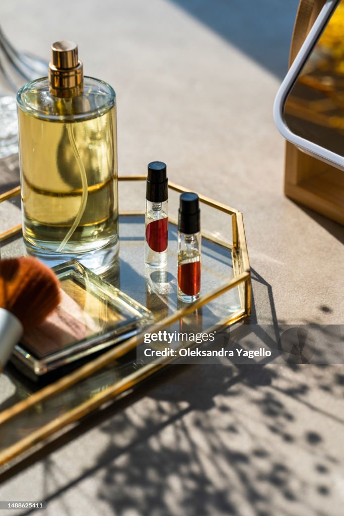 Cosmetic products and mirror on table. Unrecognizable bottles of perfume and samplers. Beauty concept