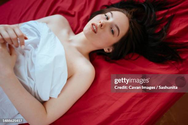 woman lying on a red sheet with her hair down - body lying down stock pictures, royalty-free photos & images