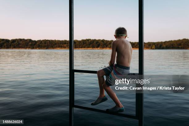 young boy fishing in lake off dock at sunset - branson imagens e fotografias de stock