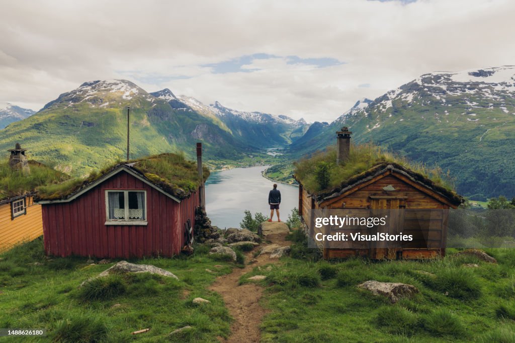 ノルウェーの古い木造住宅で風光明媚な山の谷を熟考する男性の背面図