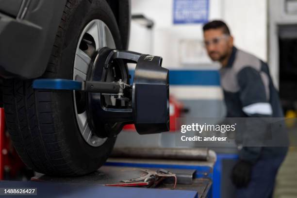 mecánico alineando un neumático de automóvil en un taller de reparación de automóviles - arreglo fotografías e imágenes de stock