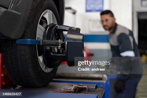 Mechanic aligning a car tire at an auto repair shop