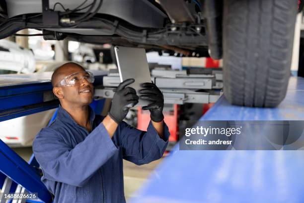 mécanicien travaillant dans un atelier de réparation automobile à l’aide d’un scanner sur une voiture - partie inférieure photos et images de collection