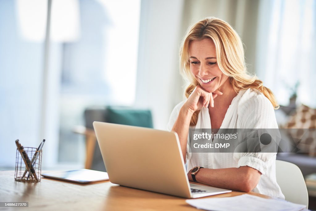 Laptop, remote work and female freelancer working on a creative project in her living room of her house. Happy, confidence and mature woman doing research for business report on computer at her home.