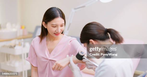 doctor examines skin with magnifier - melanoma stock pictures, royalty-free photos & images