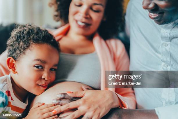 pregnant woman with husband and son at home - belly kissing stock pictures, royalty-free photos & images