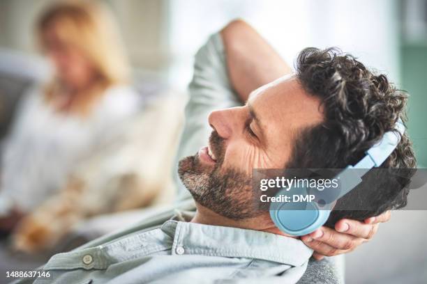 relax, music and smile with man in living room for streaming, mobile radio and podcast. technology, audio and headphones with male listening to sound at home for peace, weekend break and calm - carefree man stock pictures, royalty-free photos & images