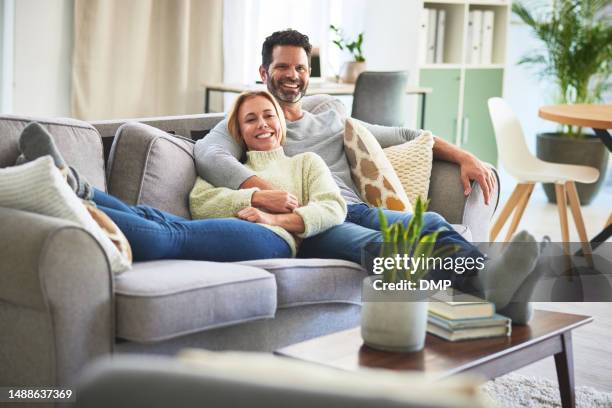 couple, smile and watching tv on sofa in living room of home, hug and bonding. television, couch and happy man and woman streaming movie, show or video and enjoying quality time together in house. - man arm around woman on couch silhouette stock pictures, royalty-free photos & images