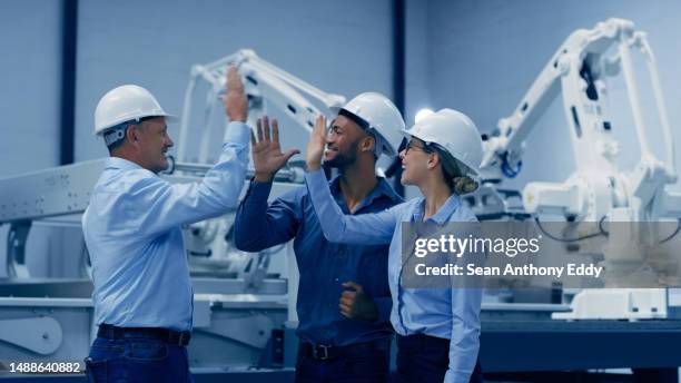 choca los cinco, robótica e ingeniería con trabajo en equipo de fábrica, éxito o celebración en el diseño de la industria 4.0. grupo de diversidad de técnicos, mujeres y hombres manos juntas para máquina o electrónica - cam fotografías e imágenes de stock