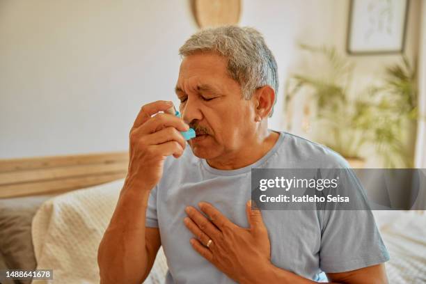 asthma, breathing and medicine with old man in home bedroom for stress, chest pain and emergency. attack, allergy and lungs medication with senior male and spray for healthcare, disease and oxygen - breathing problems stock pictures, royalty-free photos & images