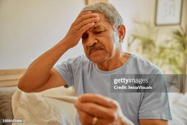 sick, thermometer and senior man in bed, checking fever and testing for temperature, home and virus. mature male, person or guy with medical equipment, health issue or problem in bedroom, cold or flu - febre imagens e fotografias de stock