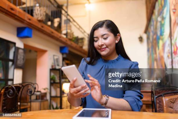 mujer joven revisando las notificaciones de la empresa de forma remota - indigenas mexicanos fotografías e imágenes de stock