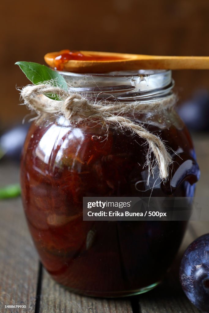 Plum jam in a transparent jar and wooden spoon,Food close up,Romania