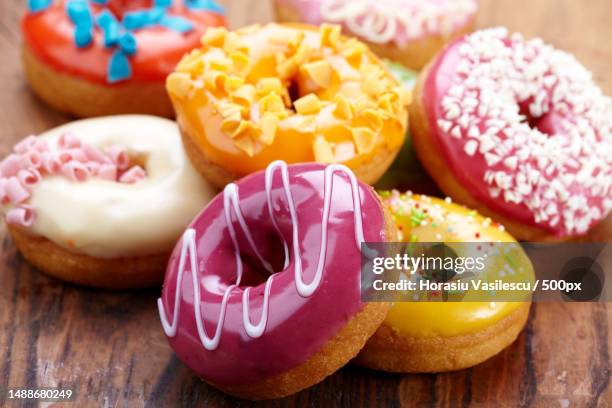 close-up of colorful donuts on wooden table - donut stock-fotos und bilder