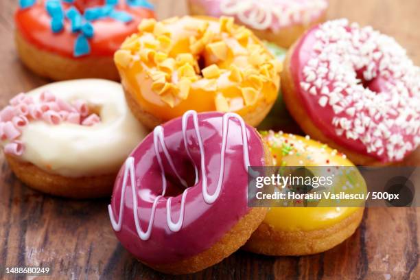 close-up of colorful donuts on wooden table - dónute imagens e fotografias de stock