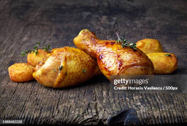 roasted chicken legs and potatoes on wooden cutting board - roast chicken table stock pictures, royalty-free photos & images