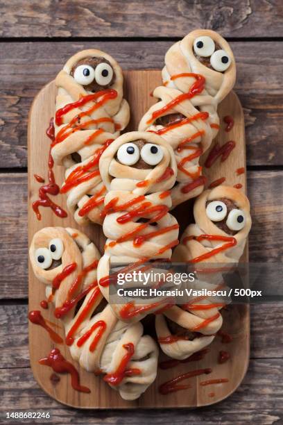 sausage meatball mummies wrapped in dough and baked scary halloween celebration party food covered with fake blood sauce decoration vintage wooden background rustic style - old fashioned candy stock pictures, royalty-free photos & images