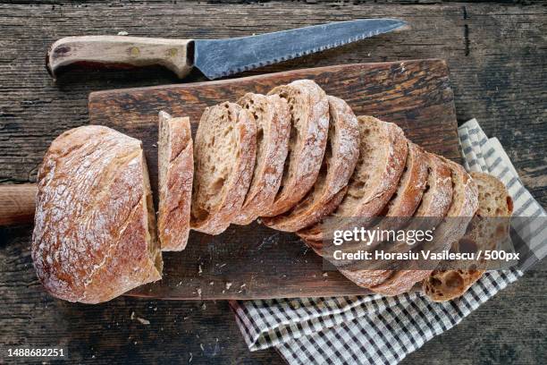 sliced bread for bruschettas on wooden cutting board - bread knife stock-fotos und bilder