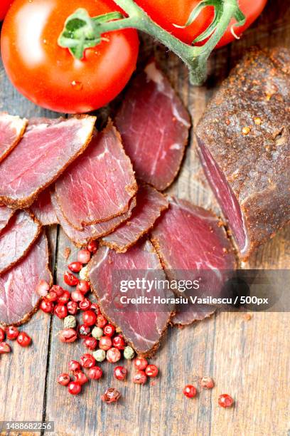 prosciutto slices,pepper corn and tomatoes on wooden table - trockenfleisch stock-fotos und bilder