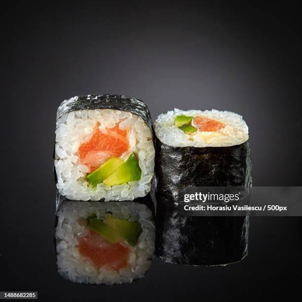 sushi with salmon and avocado on black background,romania - maki sushi stock-fotos und bilder
