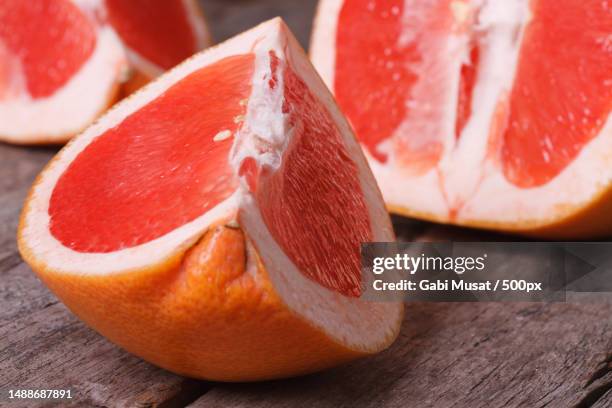 large pieces of red grapefruit on the old wooden table closeup horizontal - rubies stock pictures, royalty-free photos & images