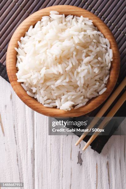 rice in a wooden bowl and chopsticks close-up vertical top view - rice plate stock pictures, royalty-free photos & images