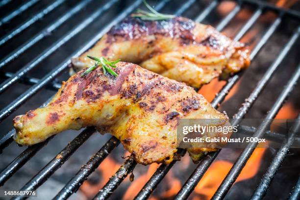 roasted chicken legs on the grill with fire - grilled chicken stock pictures, royalty-free photos & images