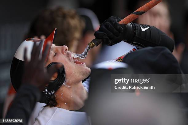 Adley Rutschman of the Baltimore Orioles celebrates in the dugout with a water hose called the 'homer hose' after hitting a two run home run during...