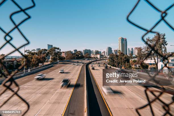 artistic long shutter photo looking through a chain link fence at early afternoon interstate 5 traffic in san diego, california near petco park - san diego street stockfoto's en -beelden