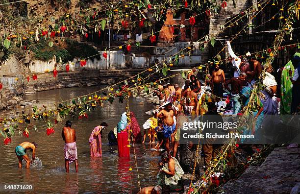 devotees bathing in bagmati river during bala chaturdashi festival at pashupatinath temple. - pashupatinath temple stock pictures, royalty-free photos & images