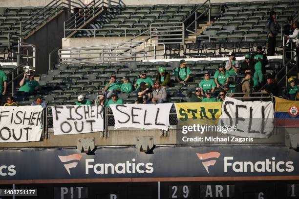 Fans of the Oakland Athletics with signs saying Managing Partner John Fisher should sell the team during the game against the Cincinnati Reds at...