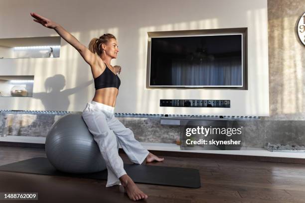 happy athletic woman exercising on fitness ball at home. - fitness ball imagens e fotografias de stock