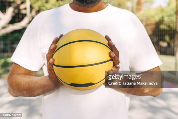 black hands with psoriasis spots holding a yellow basketball. unrecognizable person. - psoriasis stock pictures, royalty-free photos & images