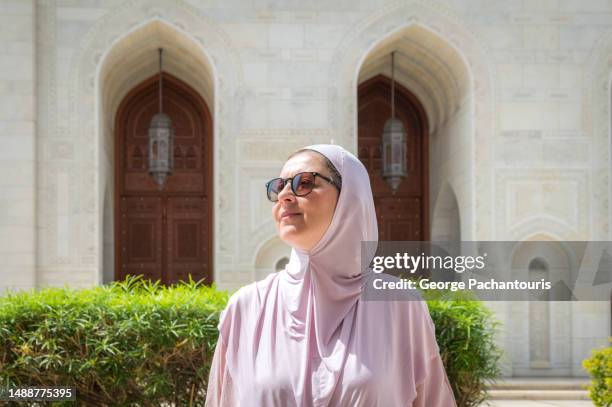 woman with hijab and sunglasses standing in the sun - fashion omani women fotografías e imágenes de stock