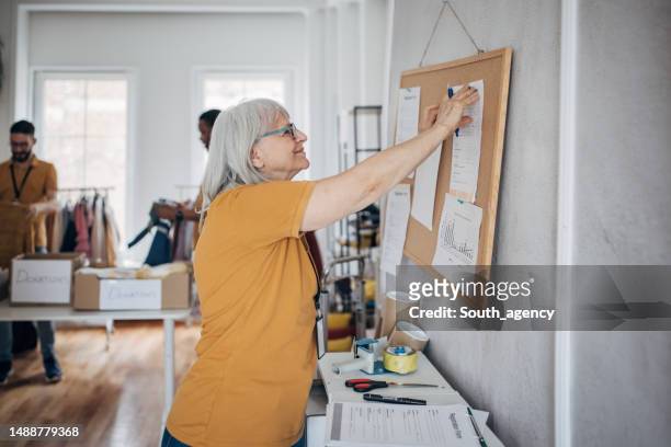 volunteer putting plan on bulletin board - reminder on pinboard stock pictures, royalty-free photos & images