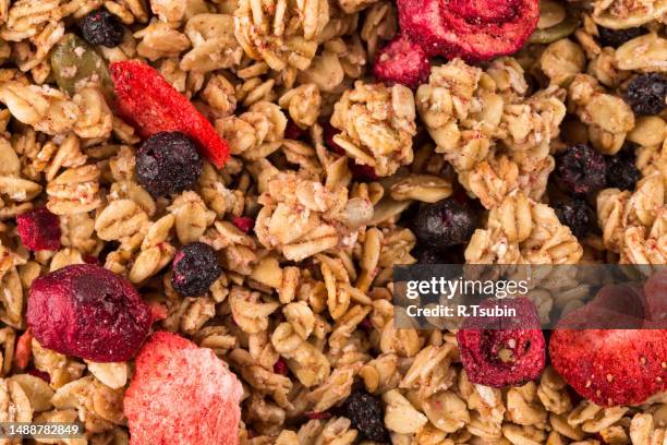 muesli cereals close up background with raisins, oat and wheat flakes, fruits, strawberry, cranberry, cherry pieces - muesli stock pictures, royalty-free photos & images