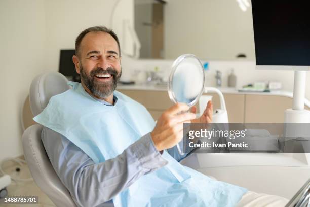 glücklicher männlicher patient, der die zahnaufhellung beim zahnarzt genießt. - dentists chair stock-fotos und bilder
