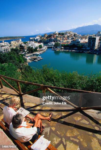 people sitting above lake voulismeni. - lake voulismeni stock pictures, royalty-free photos & images